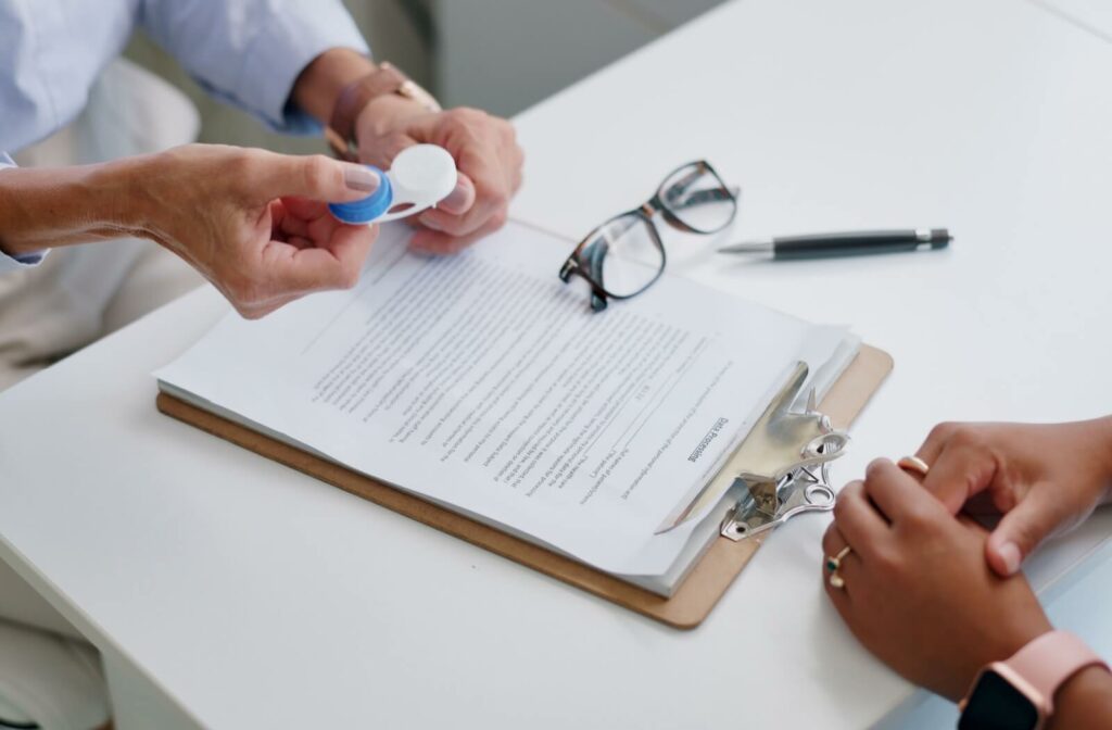 An optometrist explains a contact lens prescription to their patient before giving their patient a new set of contact lenses.
